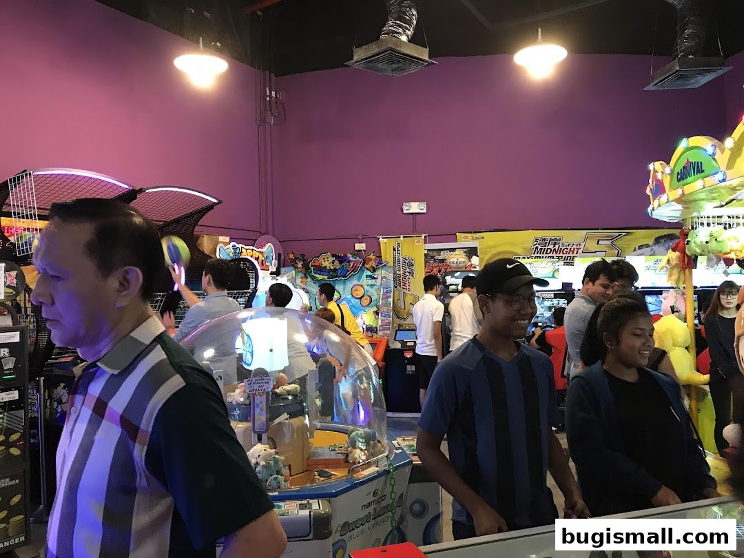 People enjoying various arcade games in a brightly lit entertainment center.