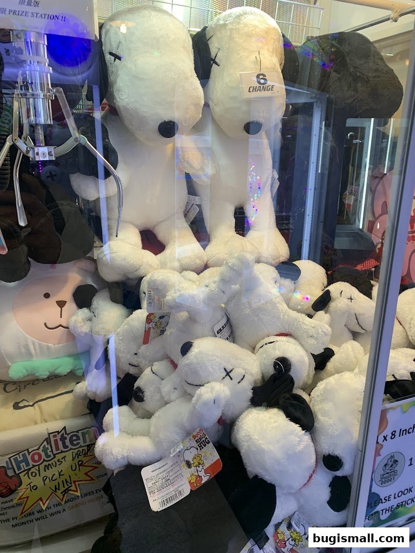 A claw machine filled with Snoopy plush toys, with a sign indicating 'Prize Station'.