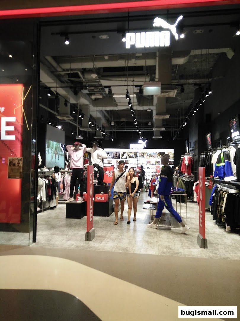 The entrance of a PUMA store with mannequins and clothing displays visible inside.