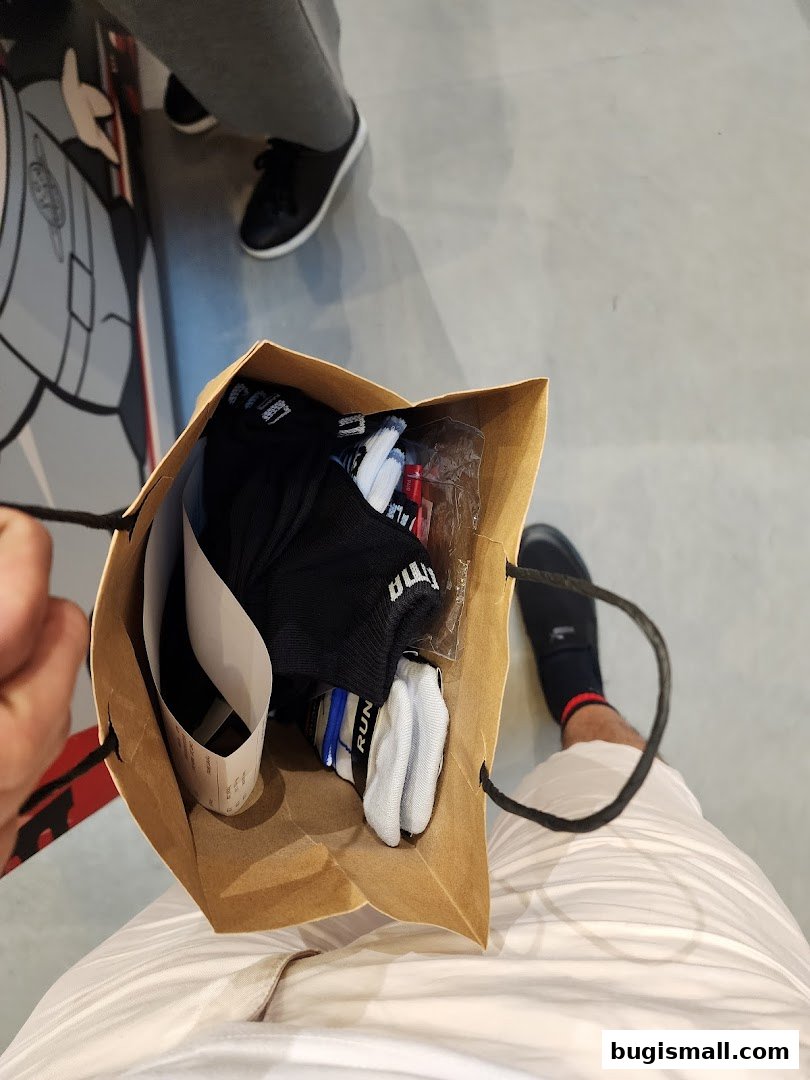 A shopping bag filled with PUMA socks and a receipt, held by a person.