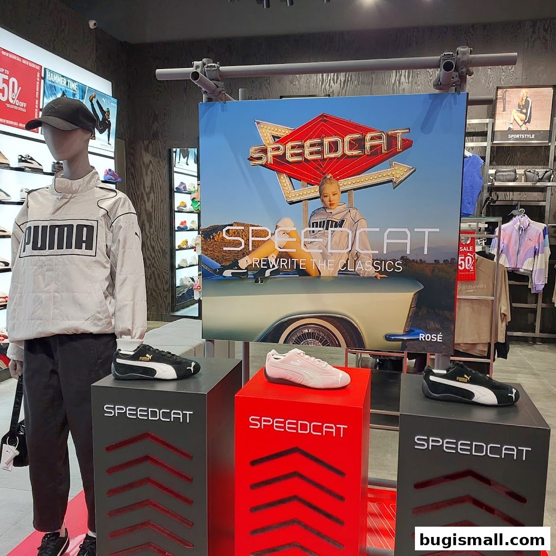 Puma store display featuring Speedcat shoes, a mannequin in Puma apparel, and promotional signage.