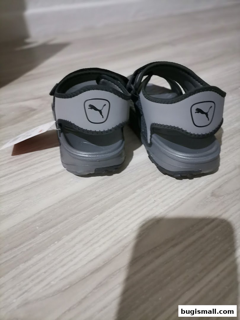A pair of grey Puma sandals with the iconic Puma logo on the heel straps.