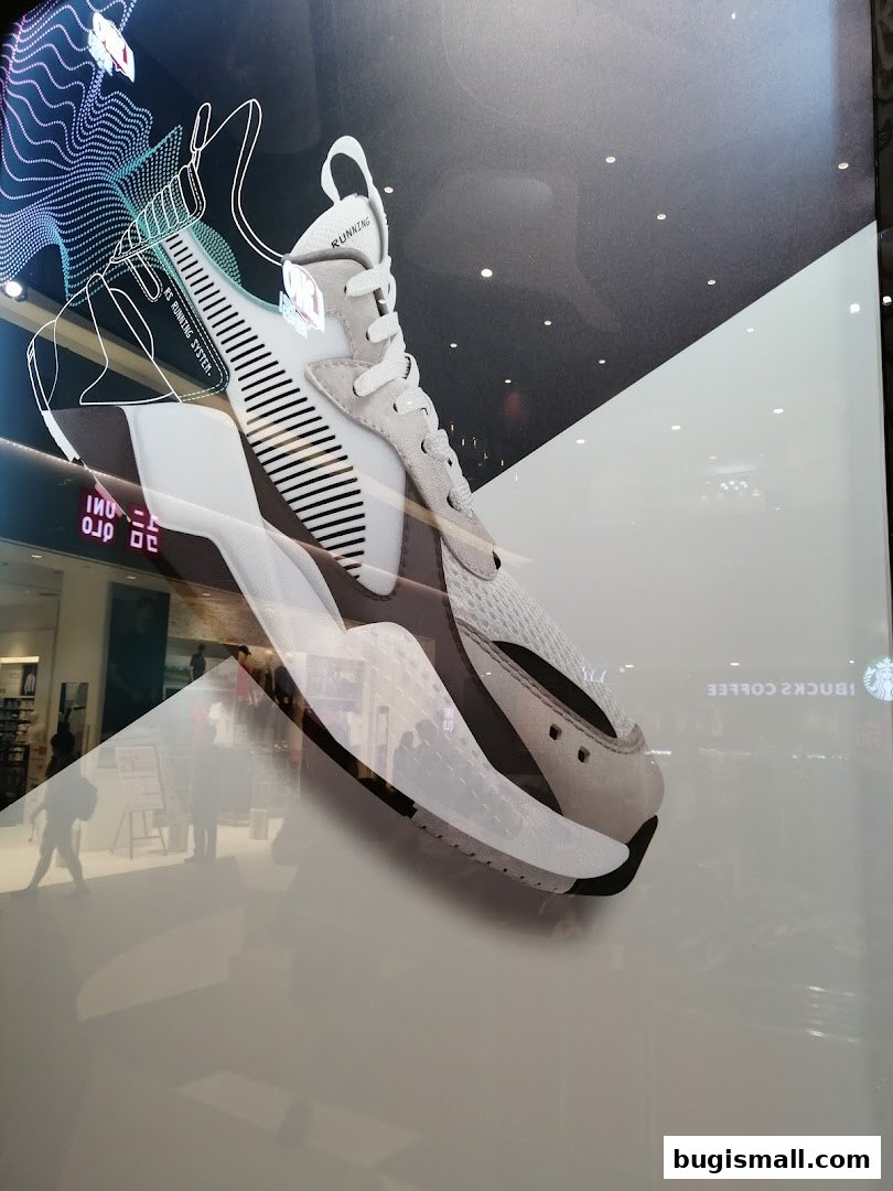 A PUMA running shoe displayed with a graphic overlay and reflections of the mall interior.