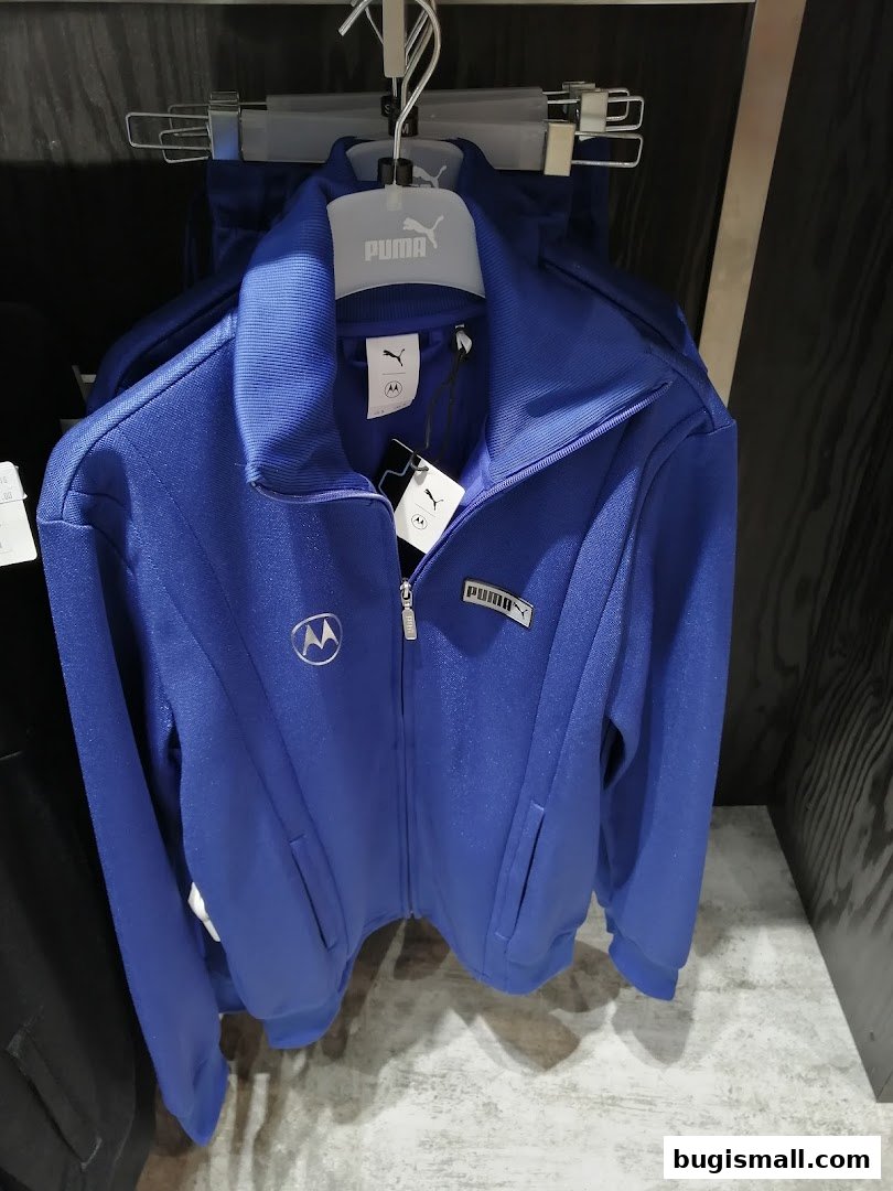 A blue Puma tracksuit jacket with a Motorola logo is displayed on a hanger.