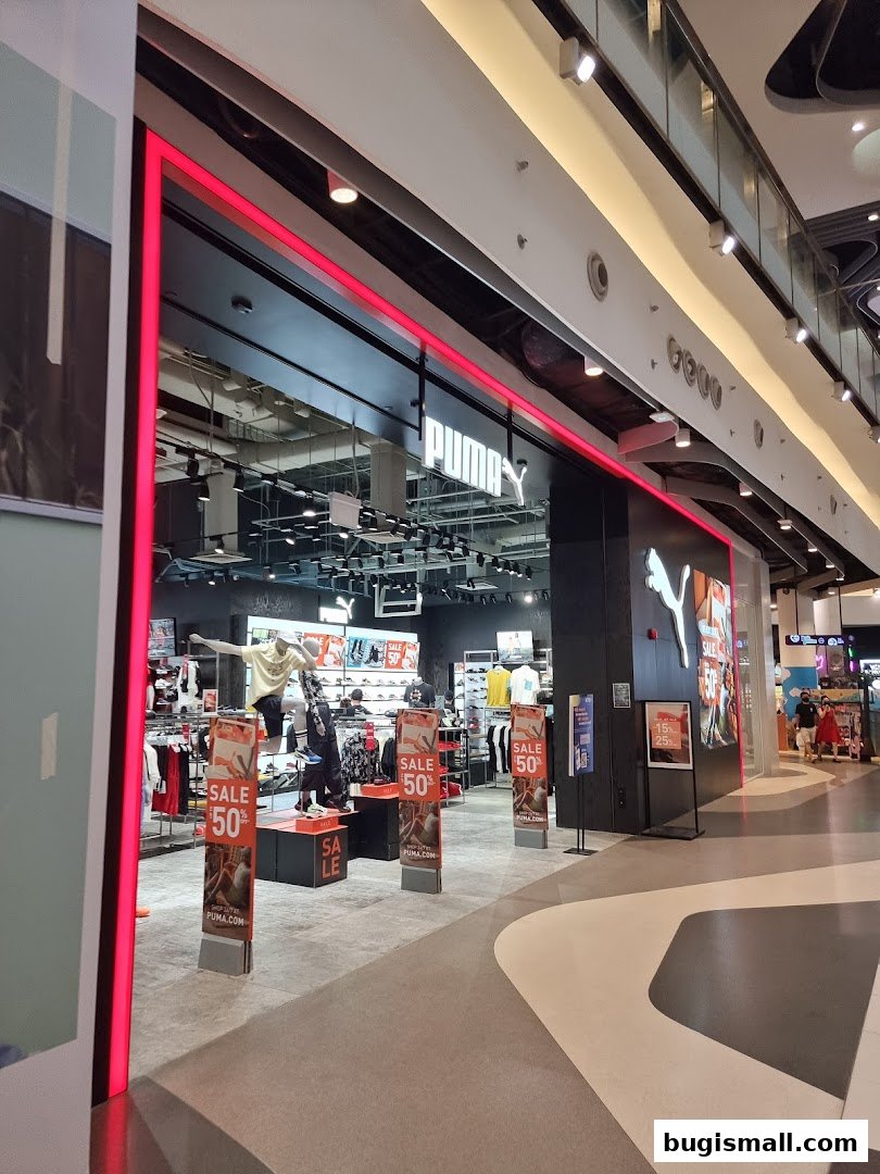 The entrance of a PUMA store with mannequins and sale signs displayed.