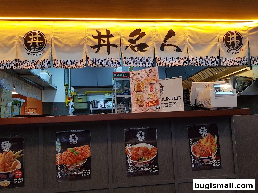 A counter display at Ramen Champion featuring food posters and a cash register.
