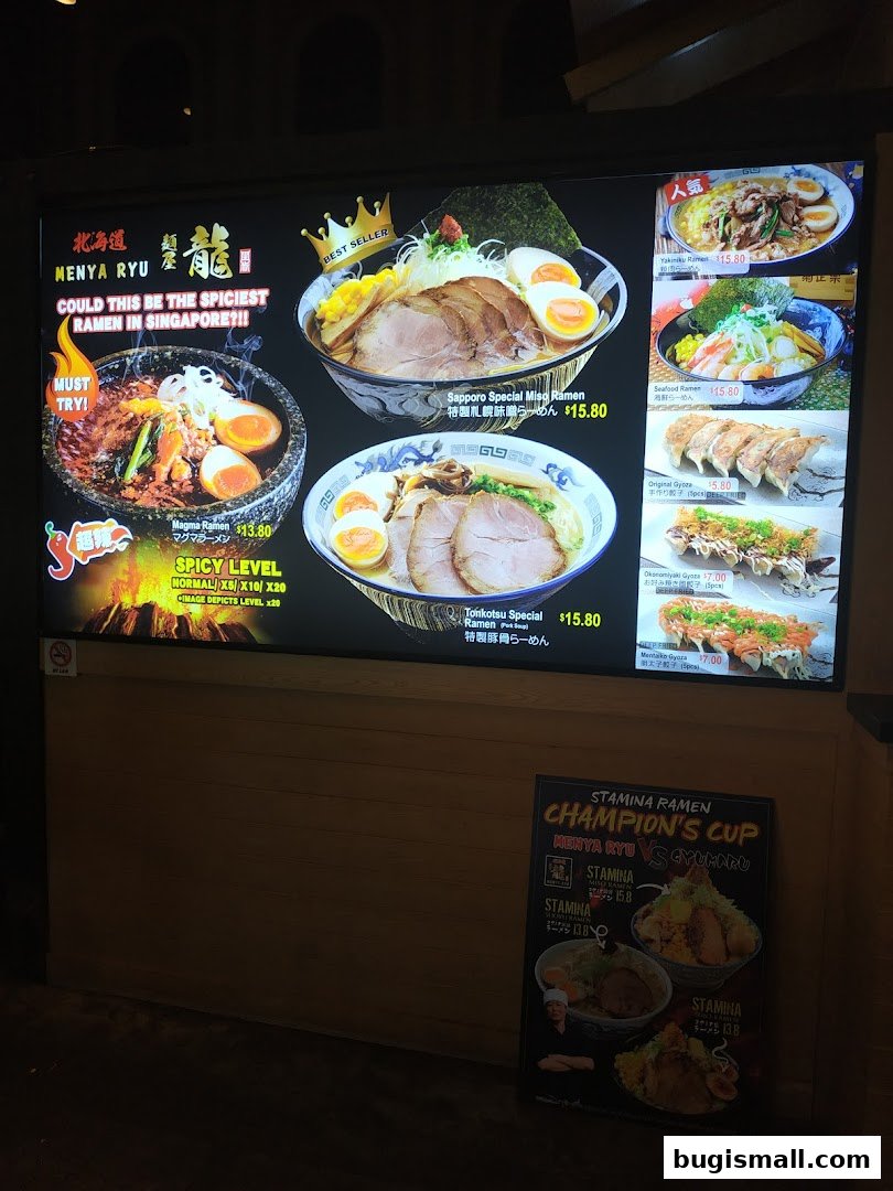 A brightly lit menu board showcasing various ramen dishes and side orders at Ramen Champion.
