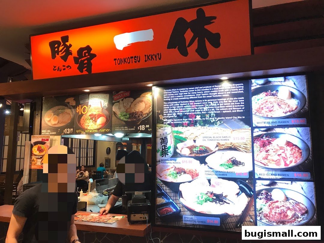 A brightly lit ramen shop counter with digital menus displaying various ramen dishes.