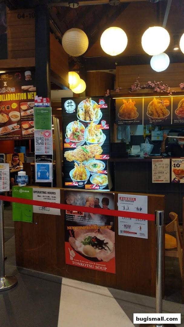 A food stall with a menu board displaying various dishes and a poster for Tonkotsu Soup.
