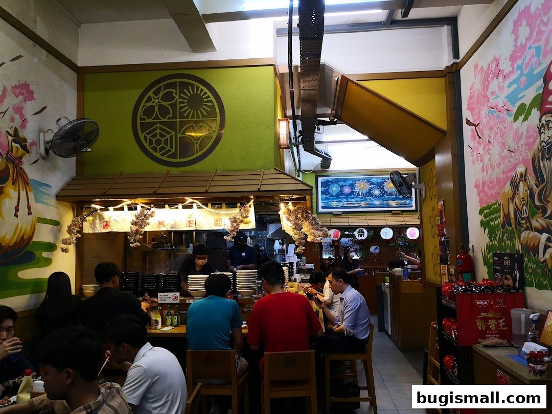 Diners enjoy ramen at a Japanese restaurant with vibrant wall art and a lively atmosphere.