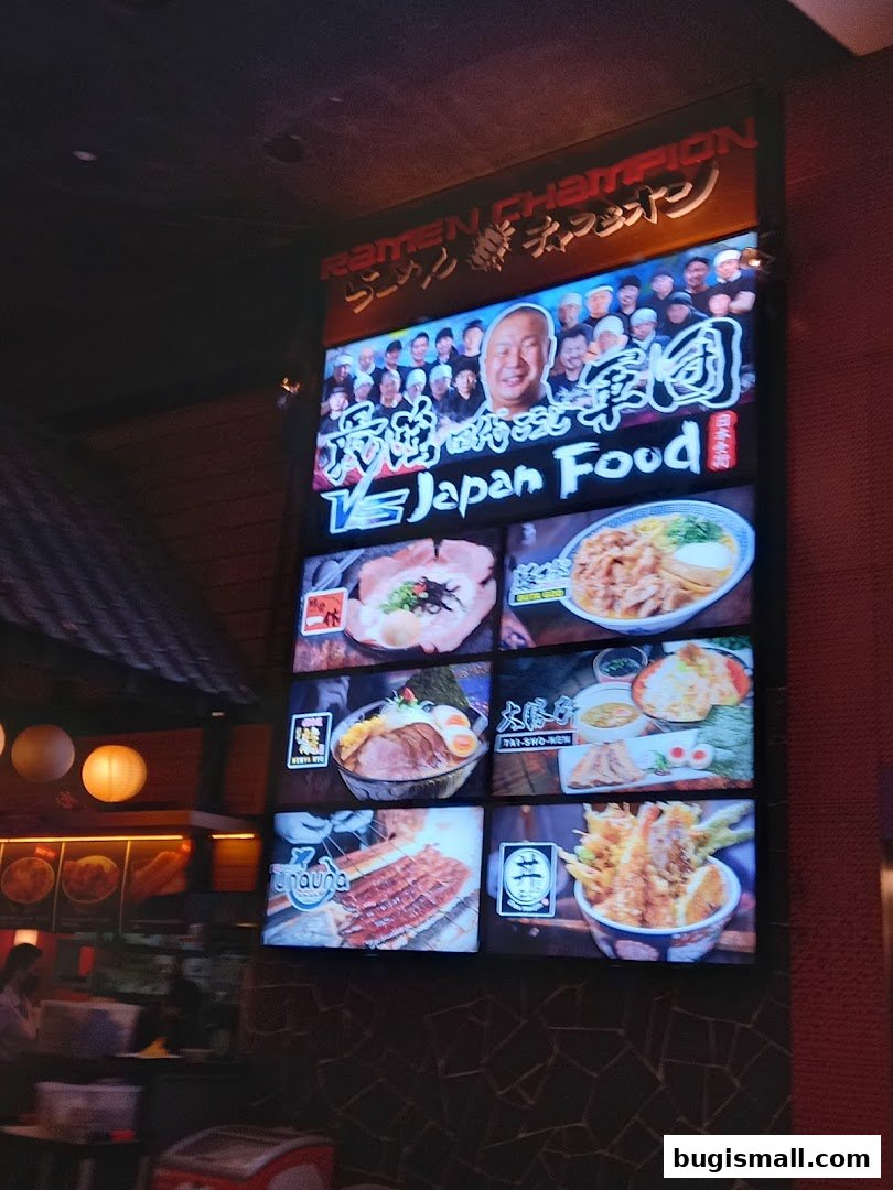 A large illuminated sign for Ramen Champion displaying various Japanese food dishes.