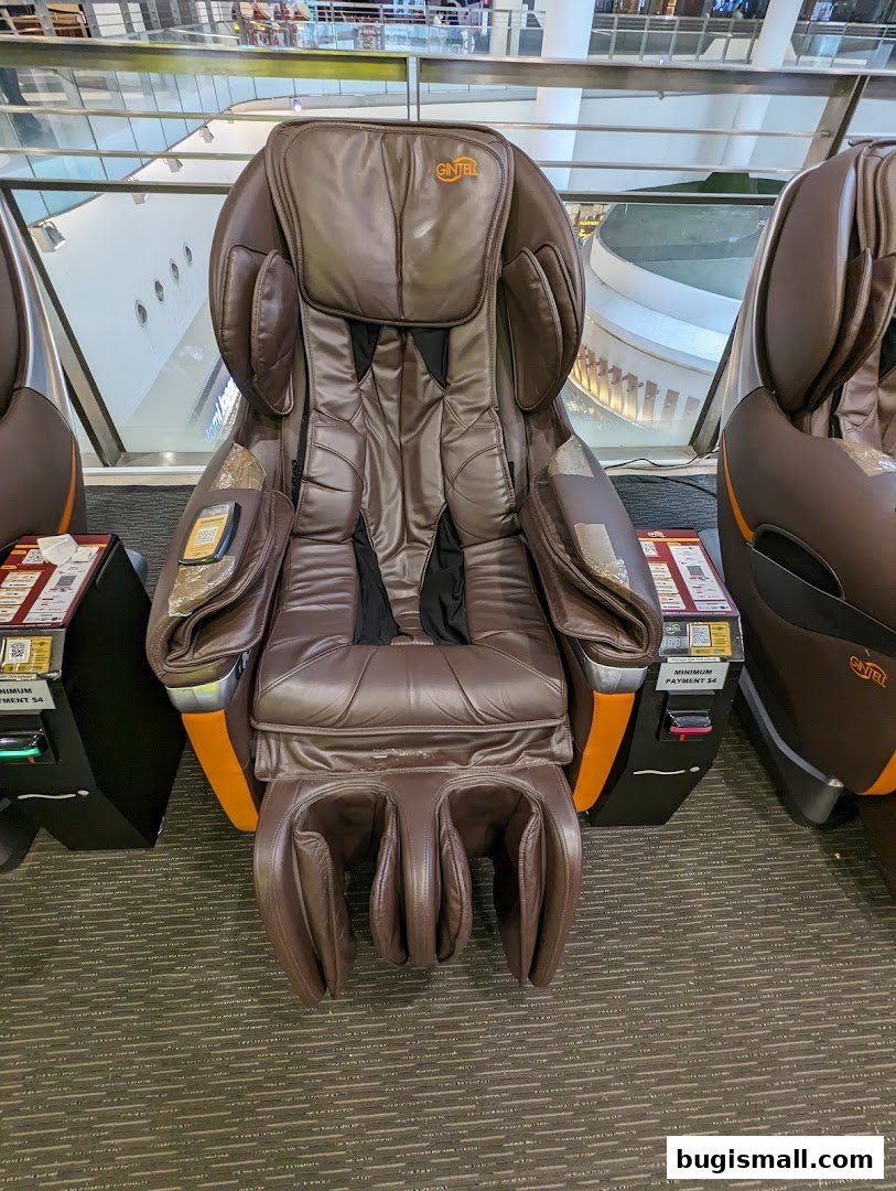 A close-up view of a brown Gintell massage chair with a payment terminal.