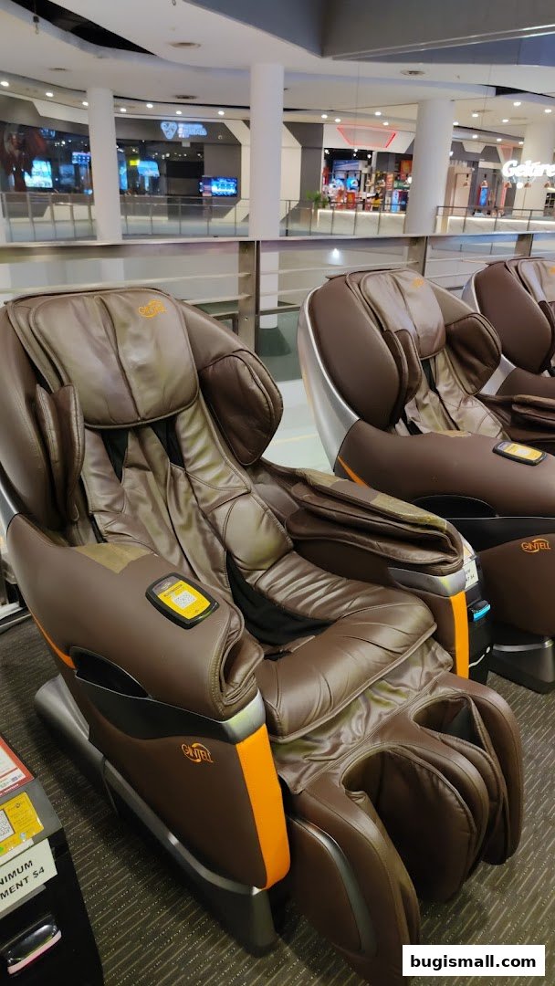 Comfortable brown massage chairs with orange accents are lined up in a mall.