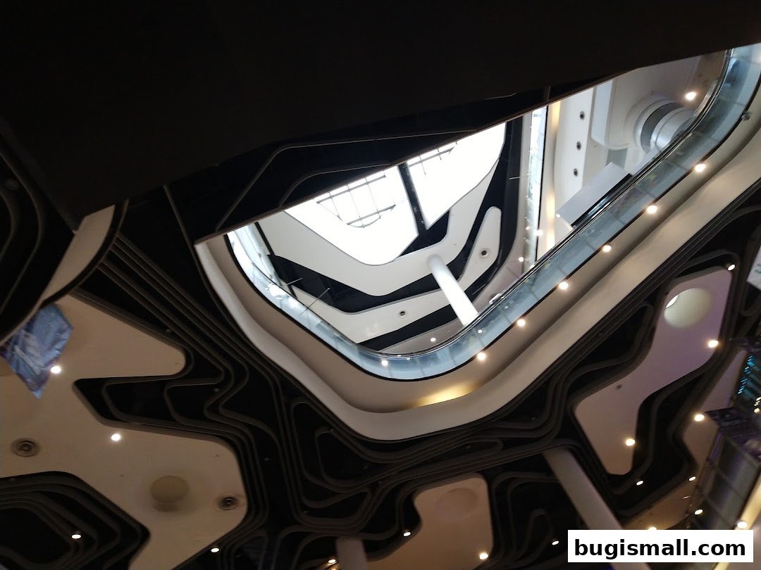 A striking view looking up at the modern architecture of a multi-level shopping mall atrium.