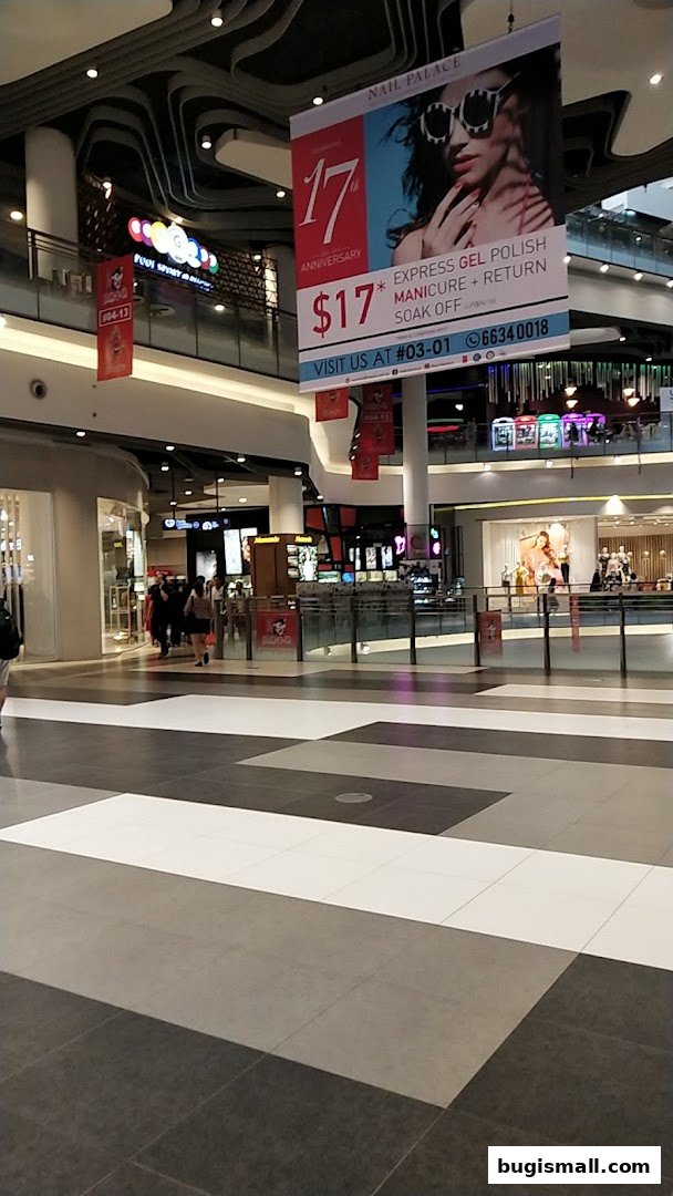 A shopping mall interior with a banner advertising Nail Palace's 17th anniversary special.