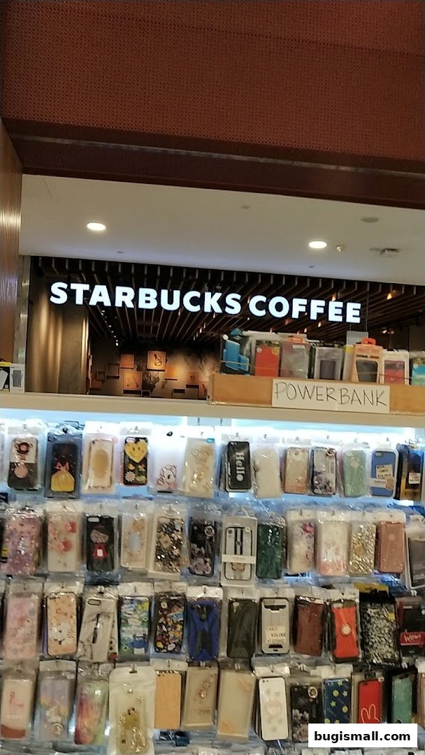 A display of phone cases and power banks in front of a Starbucks Coffee store.