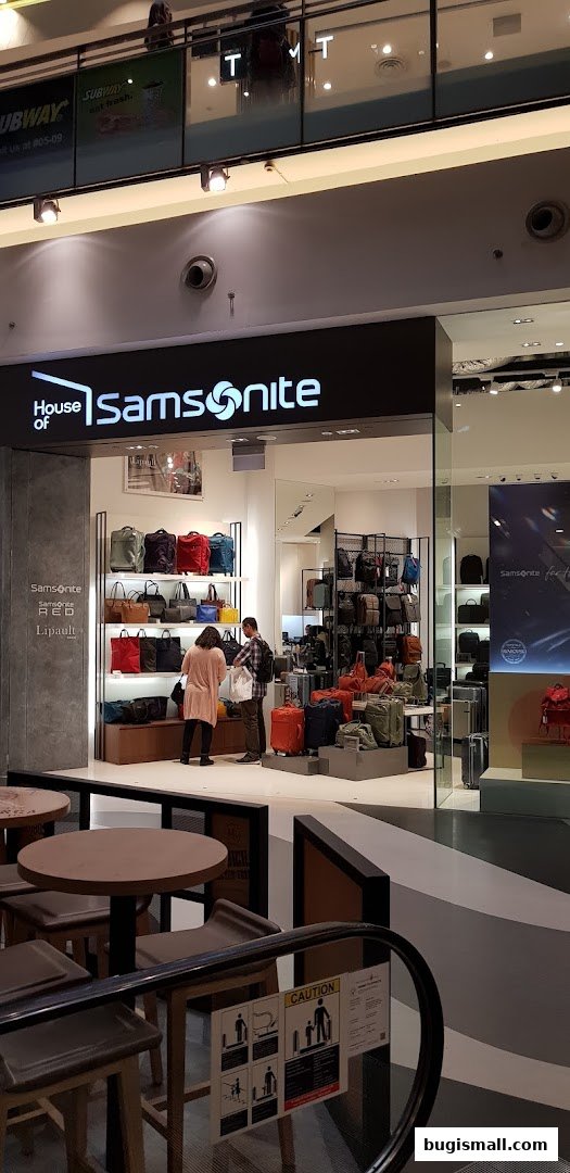 The entrance of a Samsonite store showcasing various luggage and bags, with customers browsing.