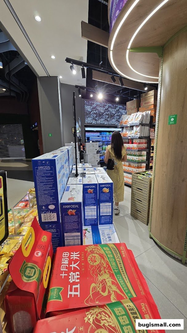 A woman shops in a supermarket aisle filled with boxes of rice and other products.