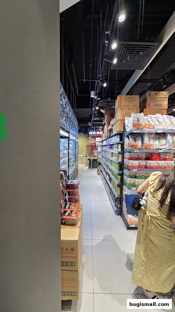 A person shops in a supermarket aisle stocked with various food products and beverages.