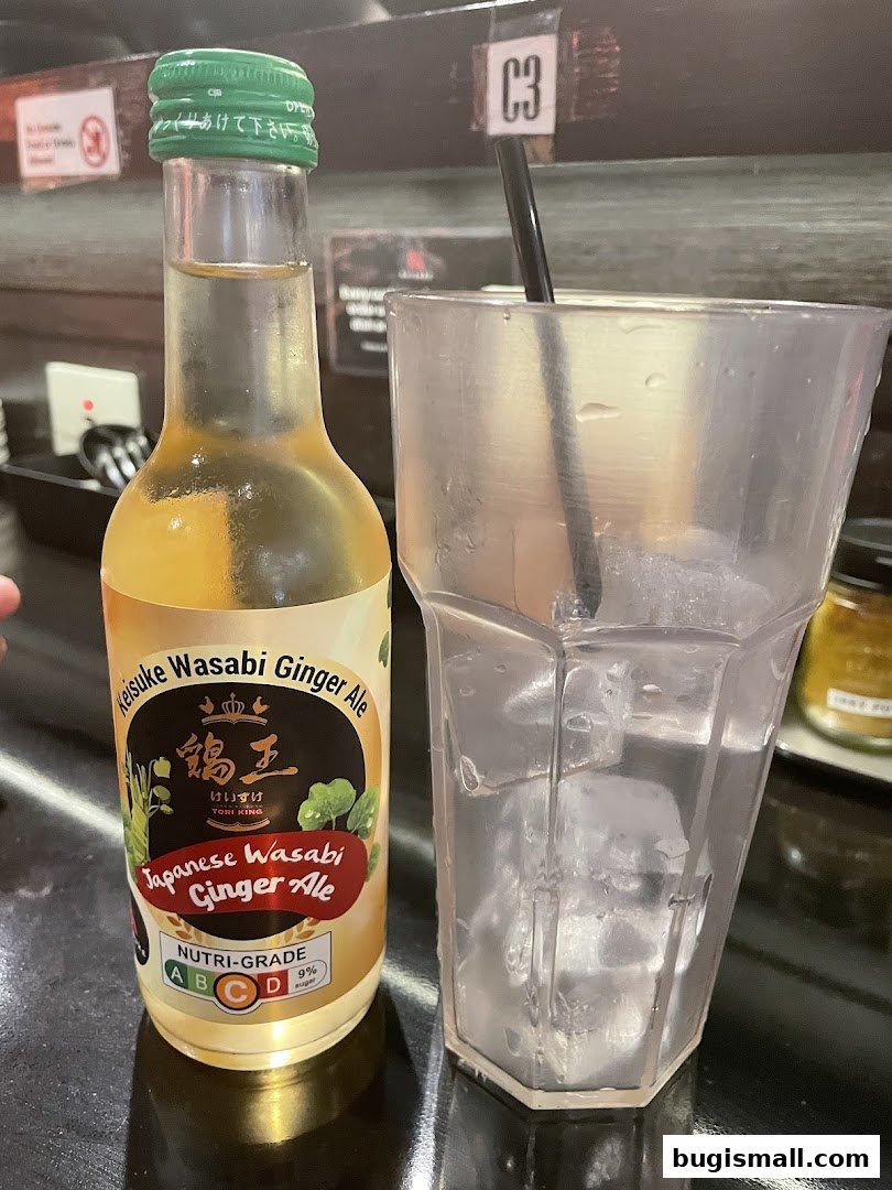 A bottle of Keisuke Japanese Wasabi Ginger Ale next to a glass of ice.