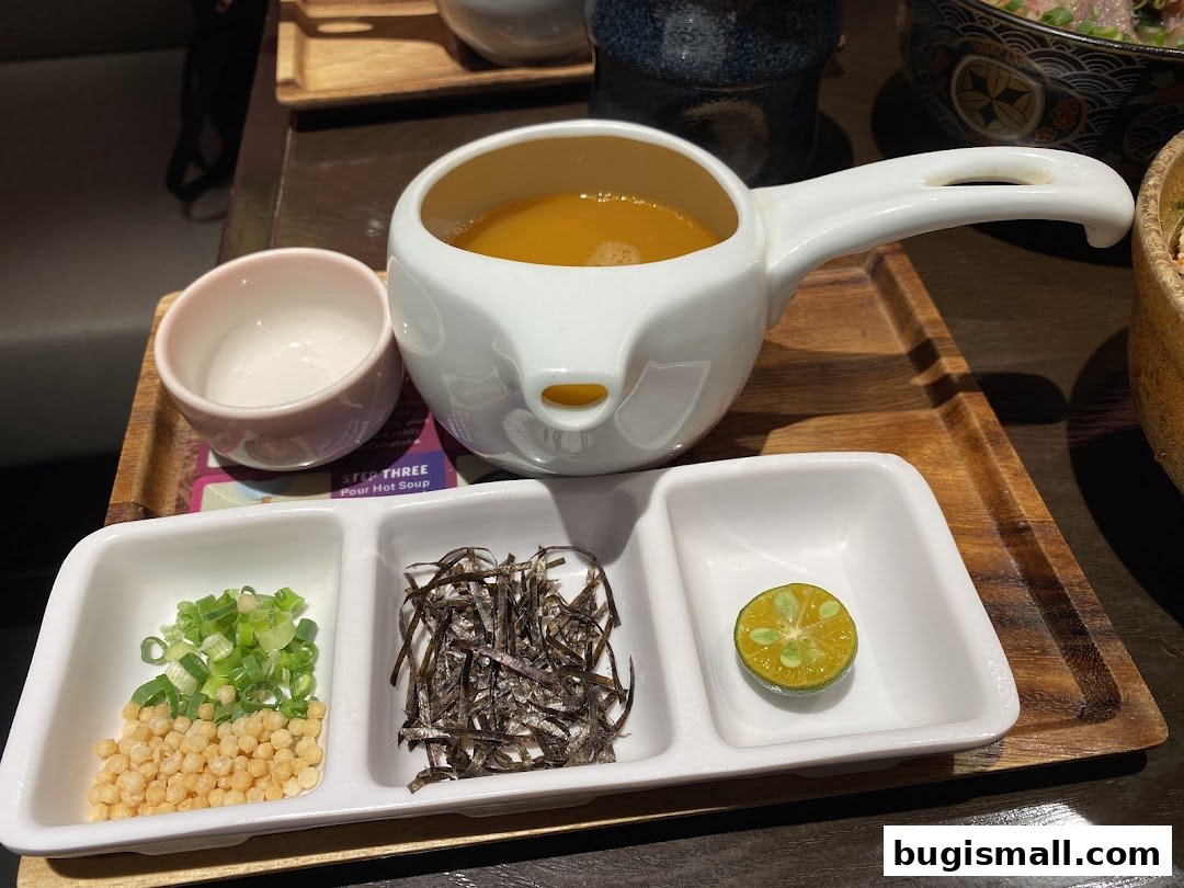 A serving of scrambled egg rice with various toppings and a side of soup.
