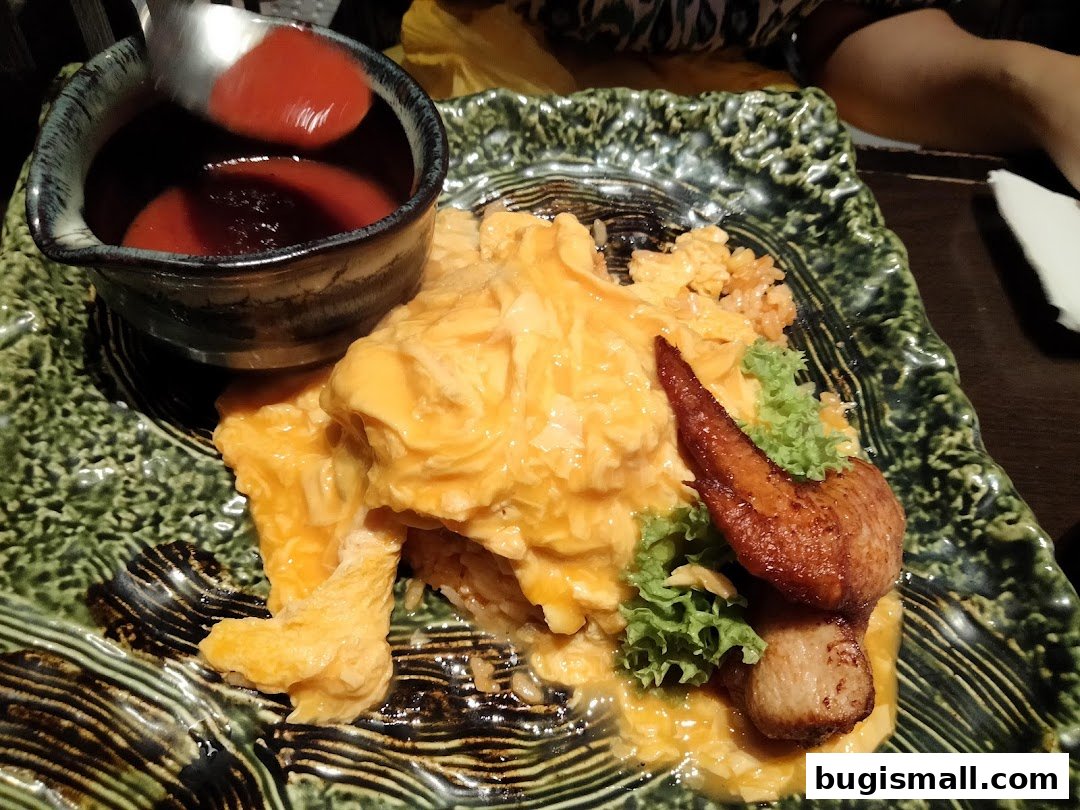A close-up of a delicious scrambled egg rice dish with a side of sauce and chicken.