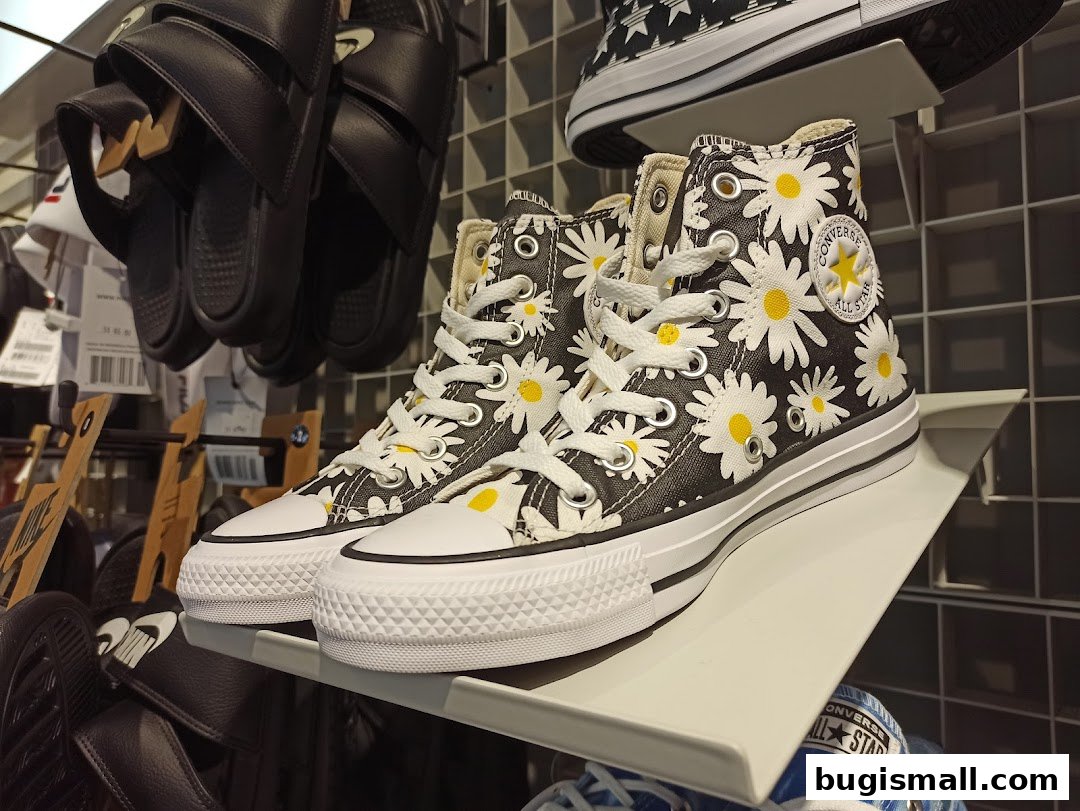 Close-up of Converse high-top sneakers with a daisy print on display.