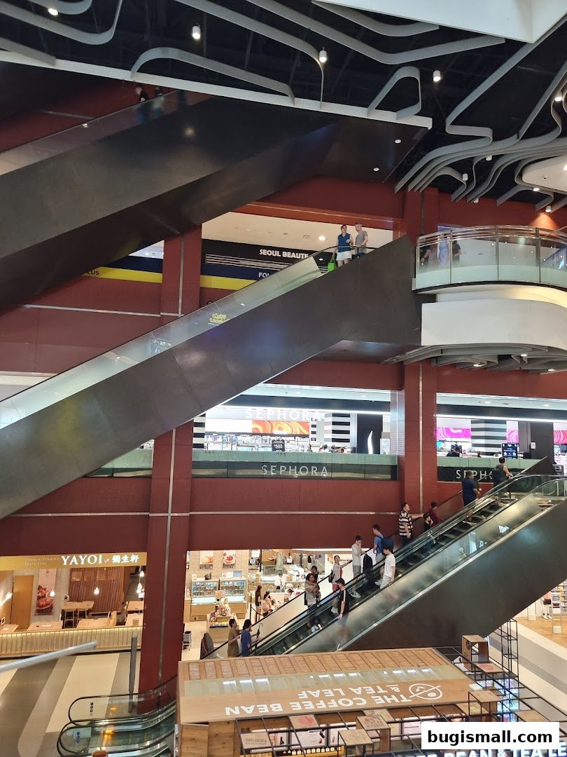 A multi-level shopping mall interior with escalators and various shops, including Sephora.