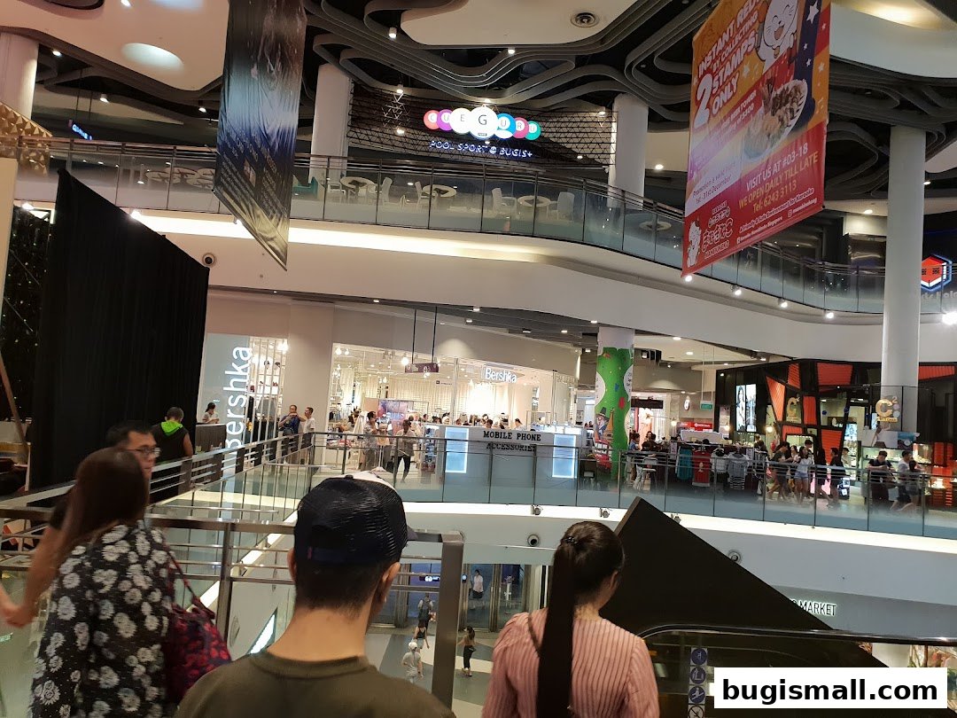 A busy shopping mall interior with various shops and shoppers on different levels.