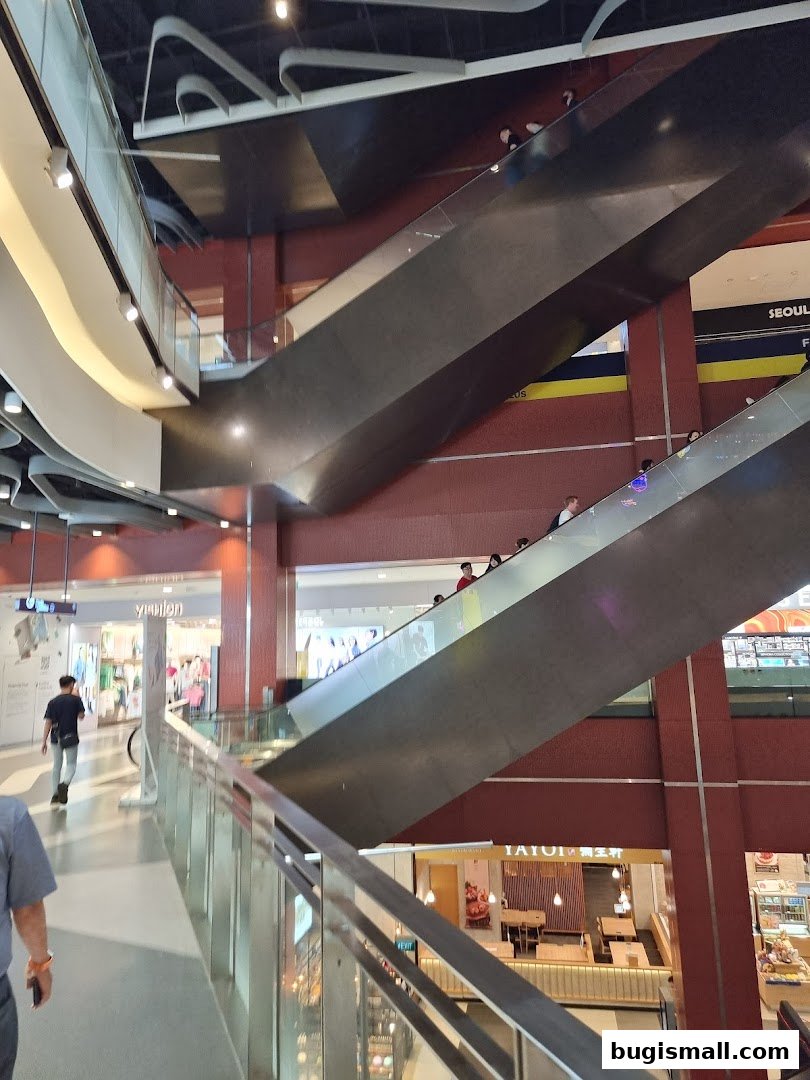 Interior view of a shopping mall with escalators and shops on multiple levels.