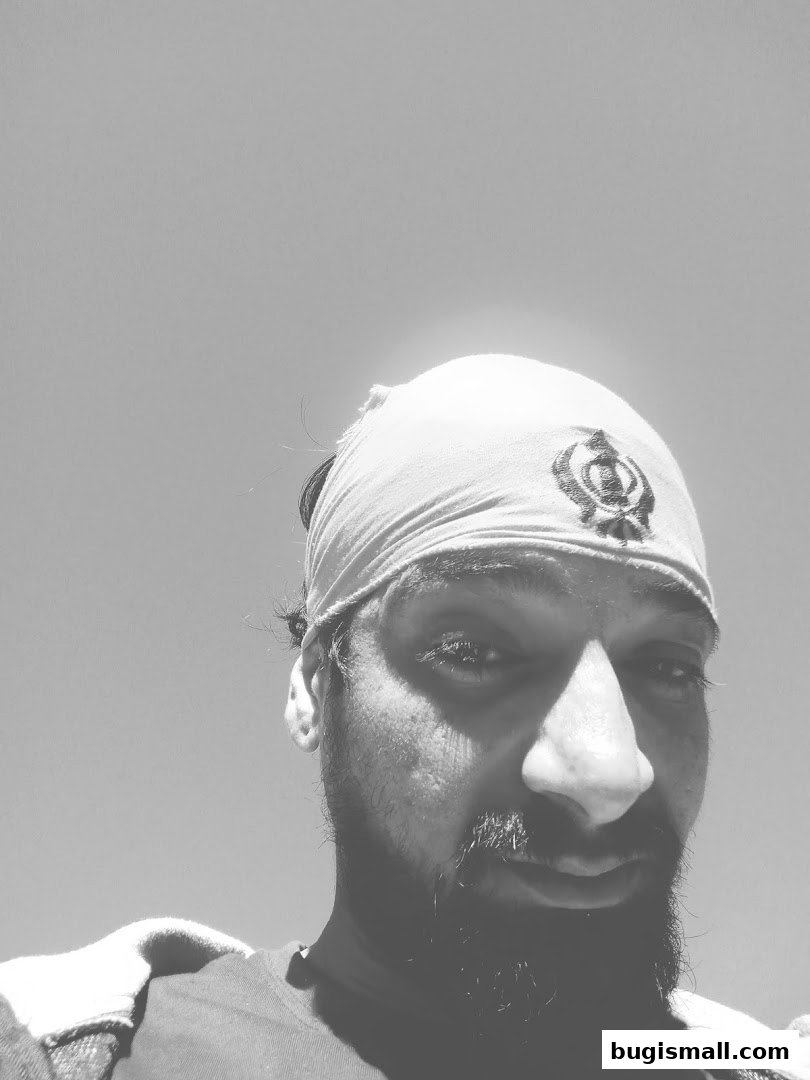 A close-up, black and white portrait of a man wearing a bandana with a symbol.