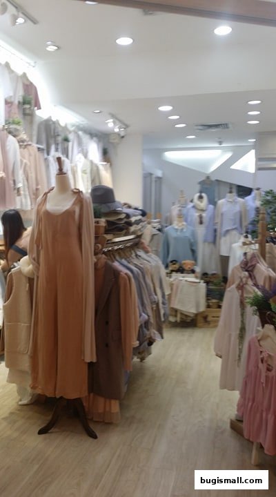 Interior view of a clothing store with mannequins displaying dresses and racks of apparel.