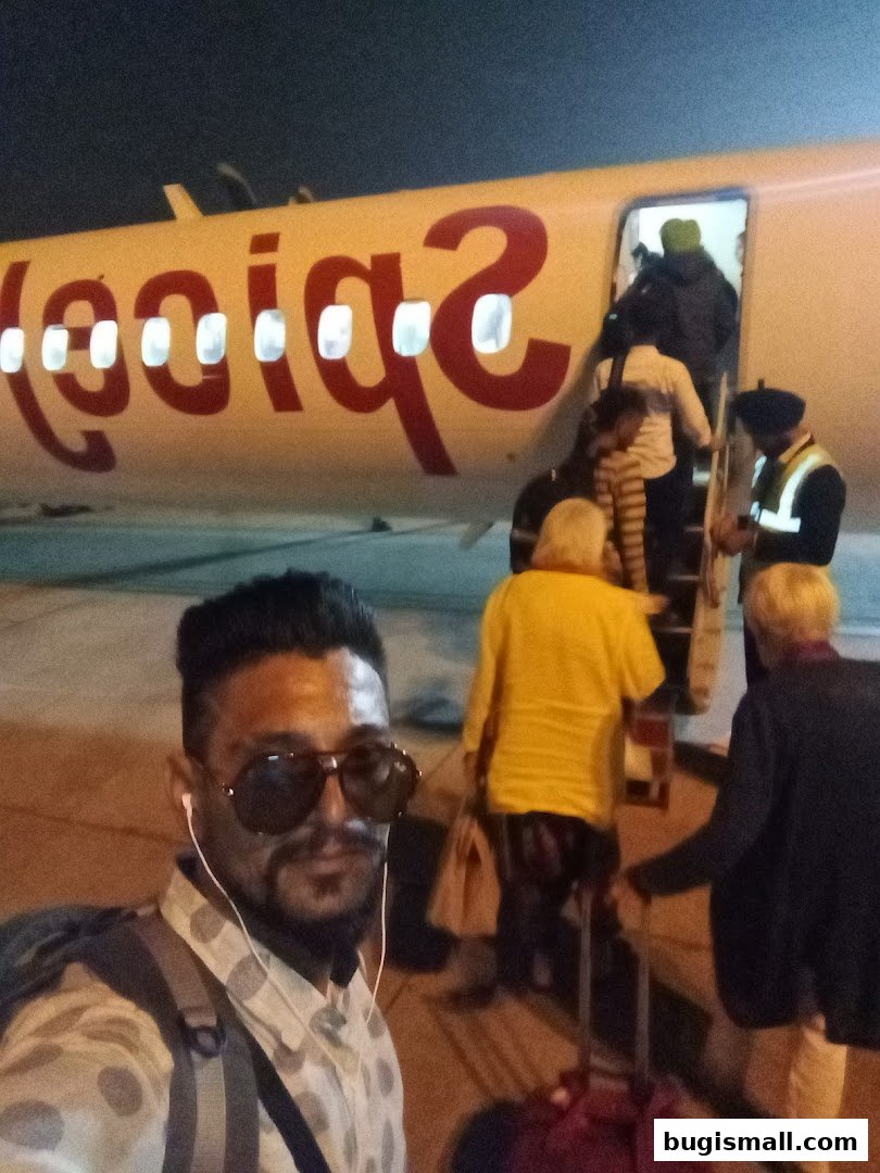 A man takes a selfie in front of a SpiceJet airplane as passengers board.