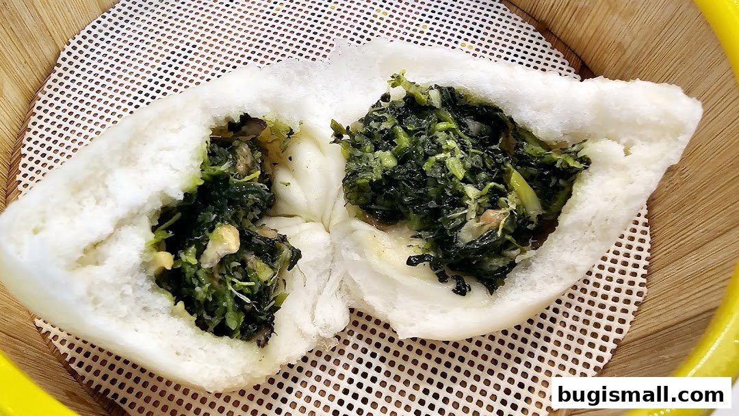 A close-up shot of a pan-fried bun filled with chopped green vegetables.