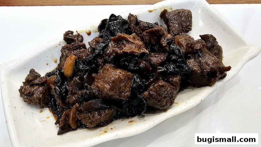 A white plate filled with braised beef and black fungus in a savory sauce.