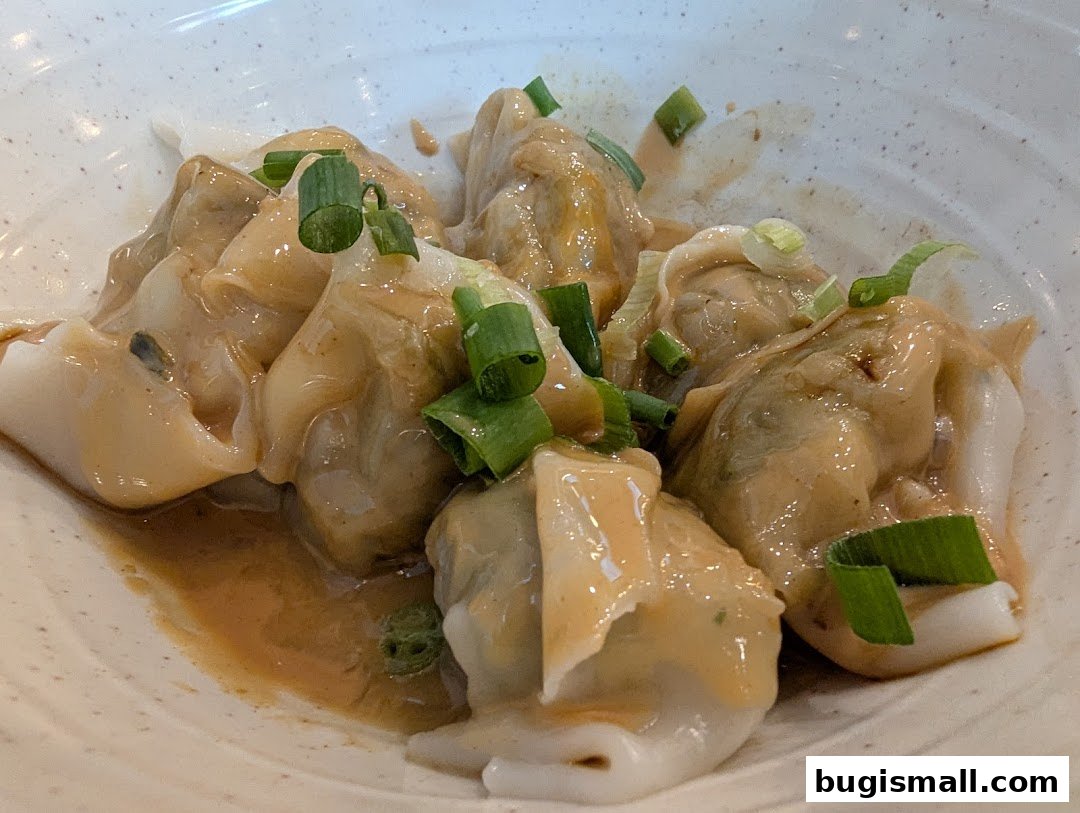 A close-up of pan-fried buns with a savory sauce and green onions.