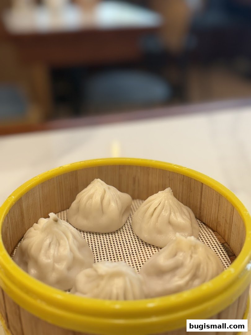 A close-up of steaming pan-fried buns in a bamboo steamer basket.