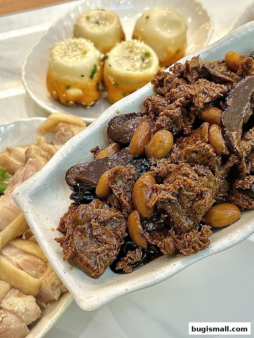 A close-up of three dishes: pan-fried buns, braised meat with nuts, and sliced chicken.