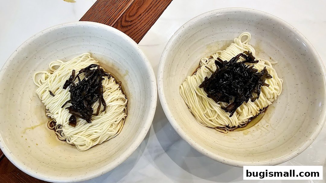 Two bowls of noodles with dark toppings, presented in rustic ceramic bowls.