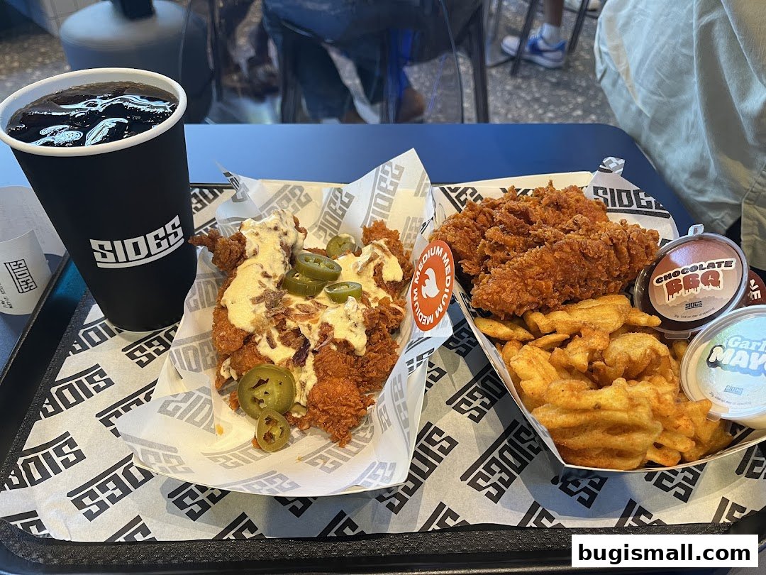 A tray of fried chicken, fries, and a drink from SIDES.