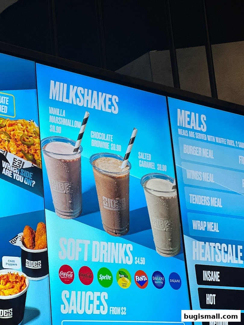 A digital menu board displaying milkshakes, soft drinks, meals, and heatscale options.