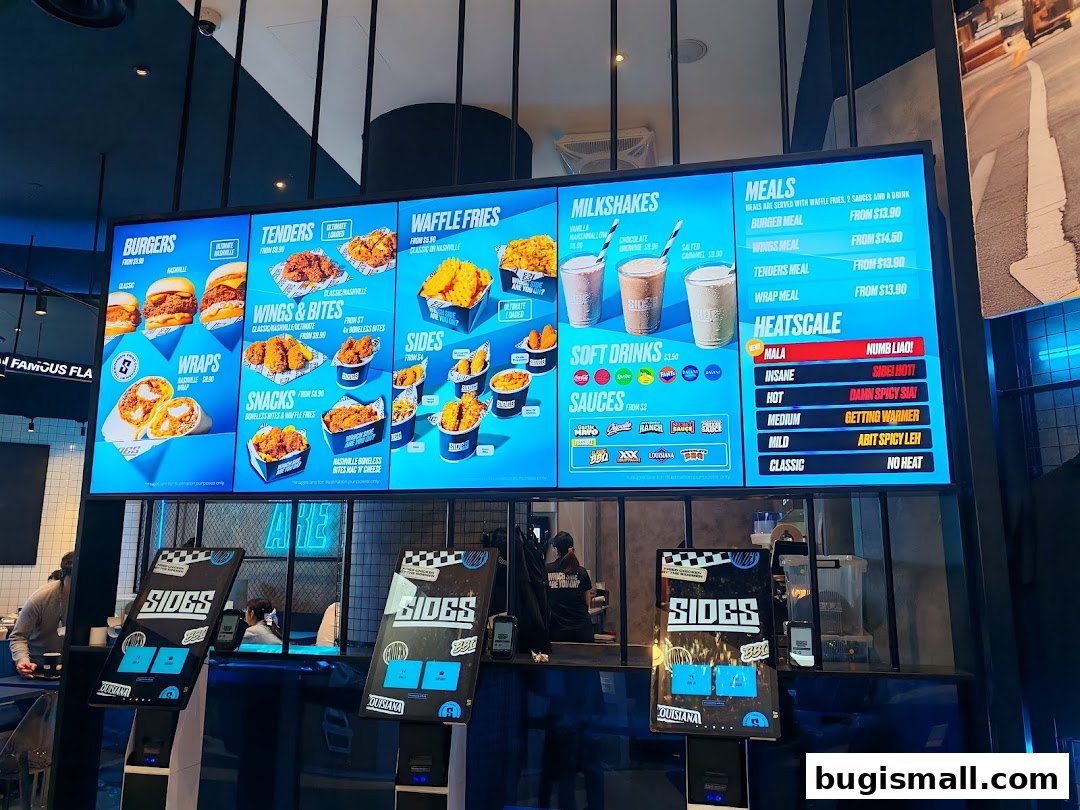 A digital menu board displaying various chicken meals, sides, milkshakes, and sauces.