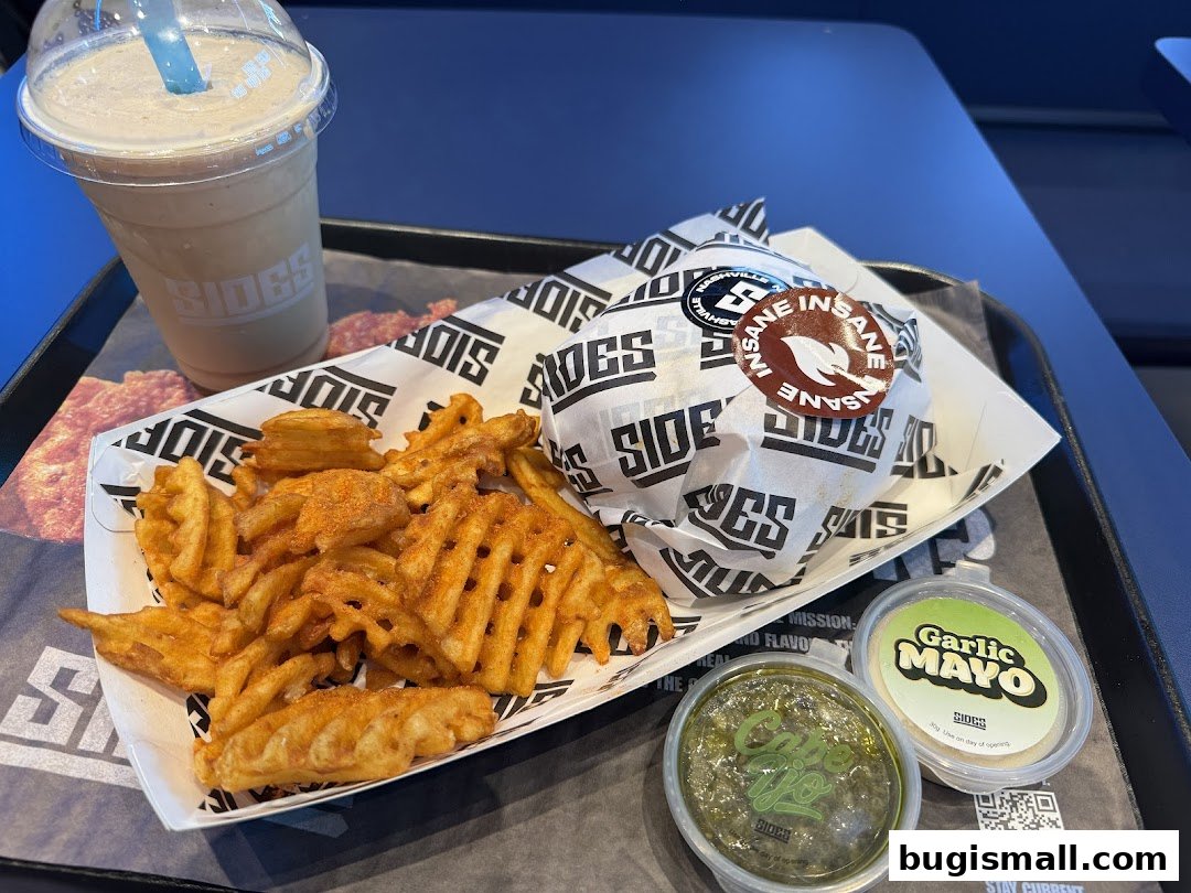 A tray with a burger, waffle fries, a milkshake, and two dipping sauces from SIDES.