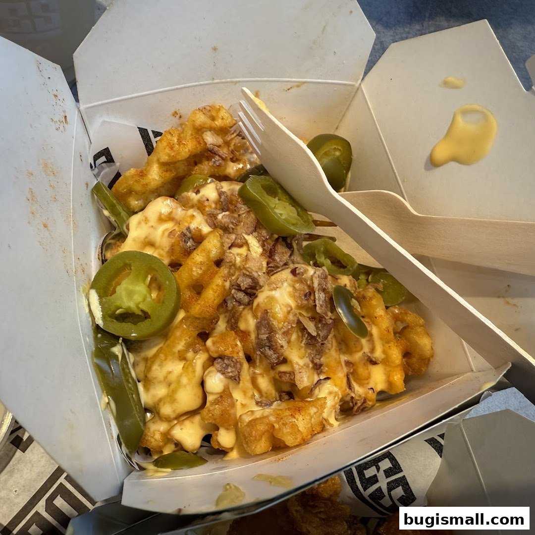 A box of loaded fries topped with cheese sauce, jalapeños, and crispy bits.
