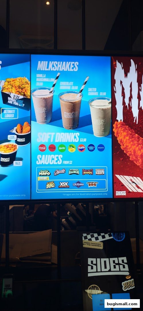 A digital menu board displaying milkshakes, soft drinks, and sauces for SIDES restaurant.