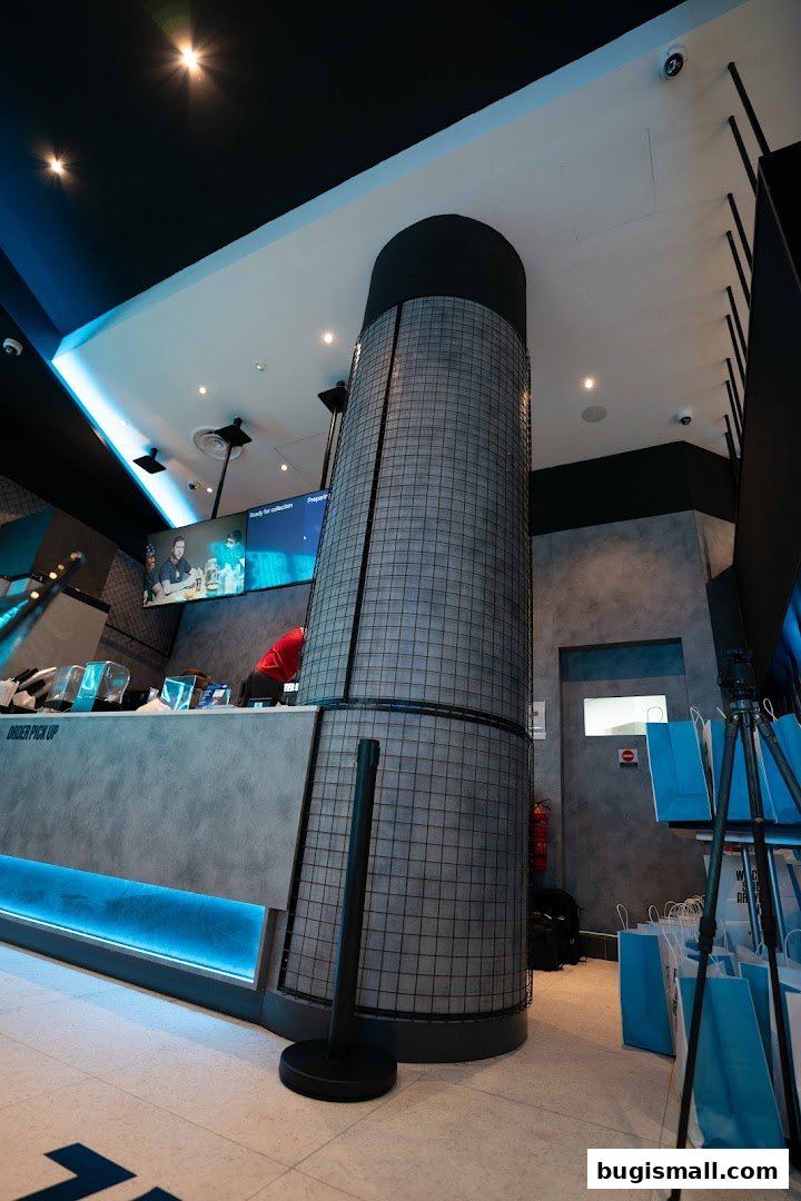 Interior view of a modern shop with a counter, screens, and blue lighting.