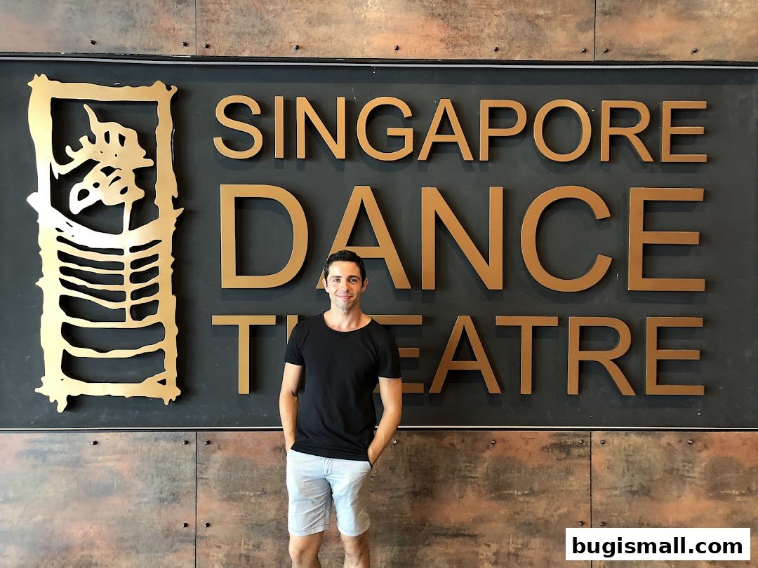 A man stands in front of the Singapore Ballet Ltd formerly Singapore Dance Theatre sign.