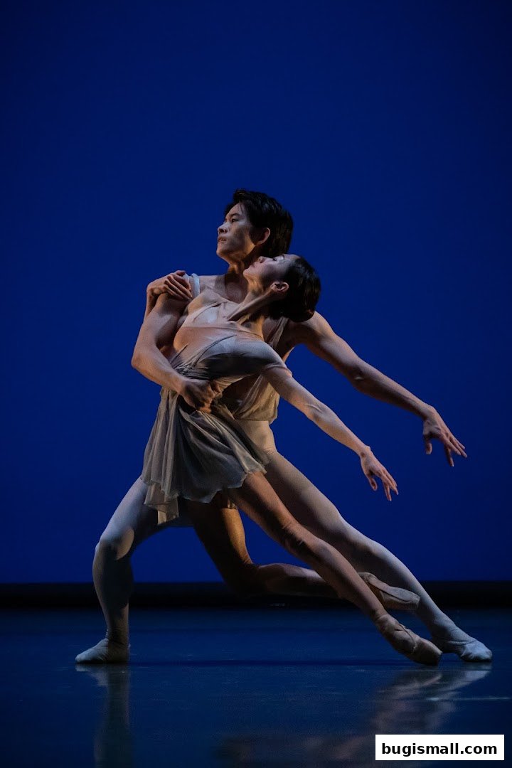Two ballet dancers in graceful poses against a vibrant blue backdrop.