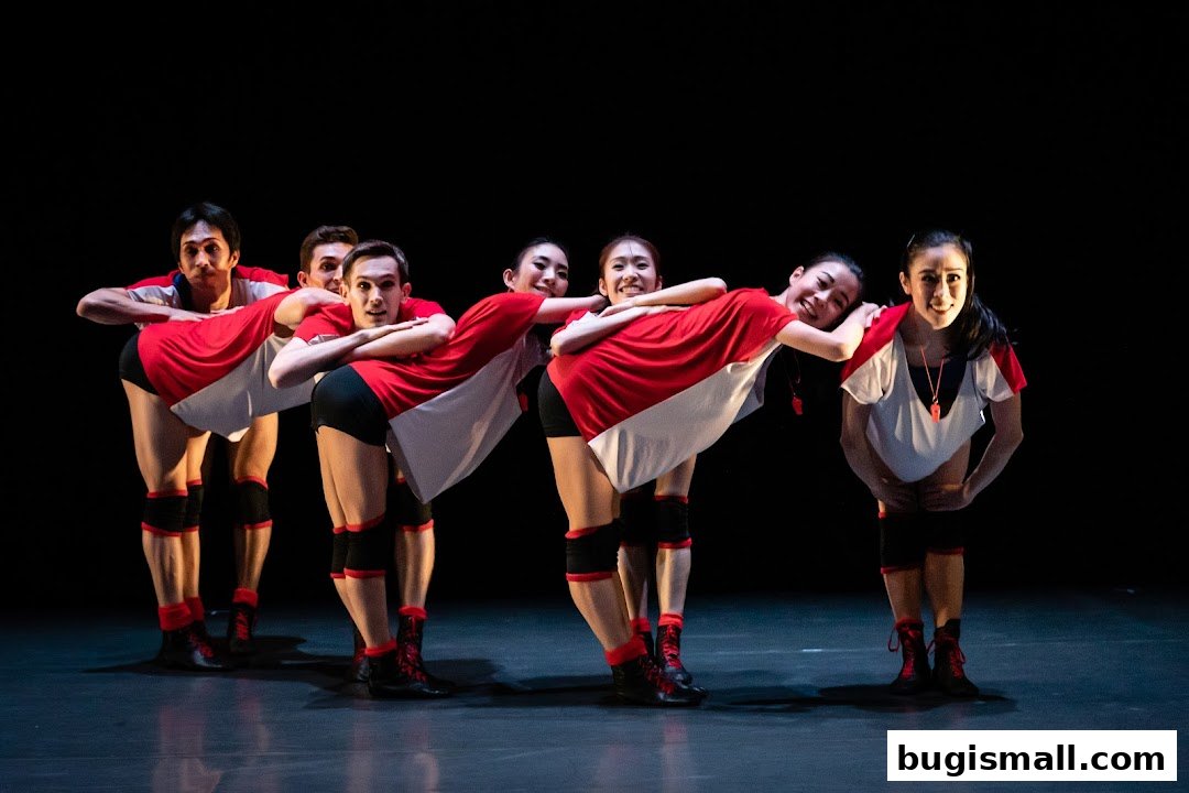 Dancers in red and white outfits pose on a dark stage.