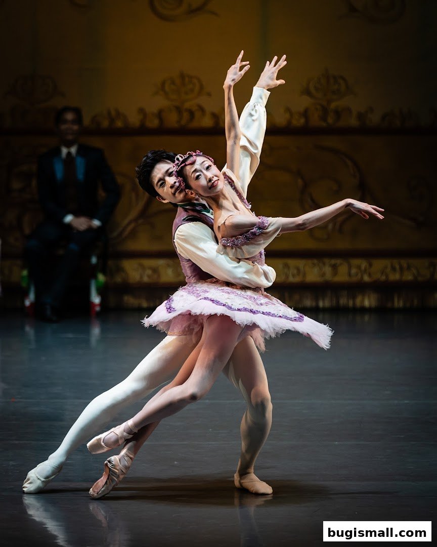Two ballet dancers in costume performing a graceful pas de deux on stage.
